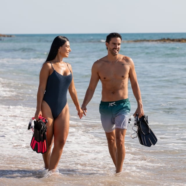 couple walking on the beach with snorkel gear