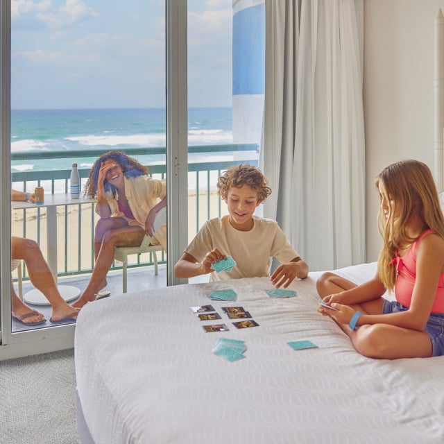 family lounging and playing cards in hotel guestroom