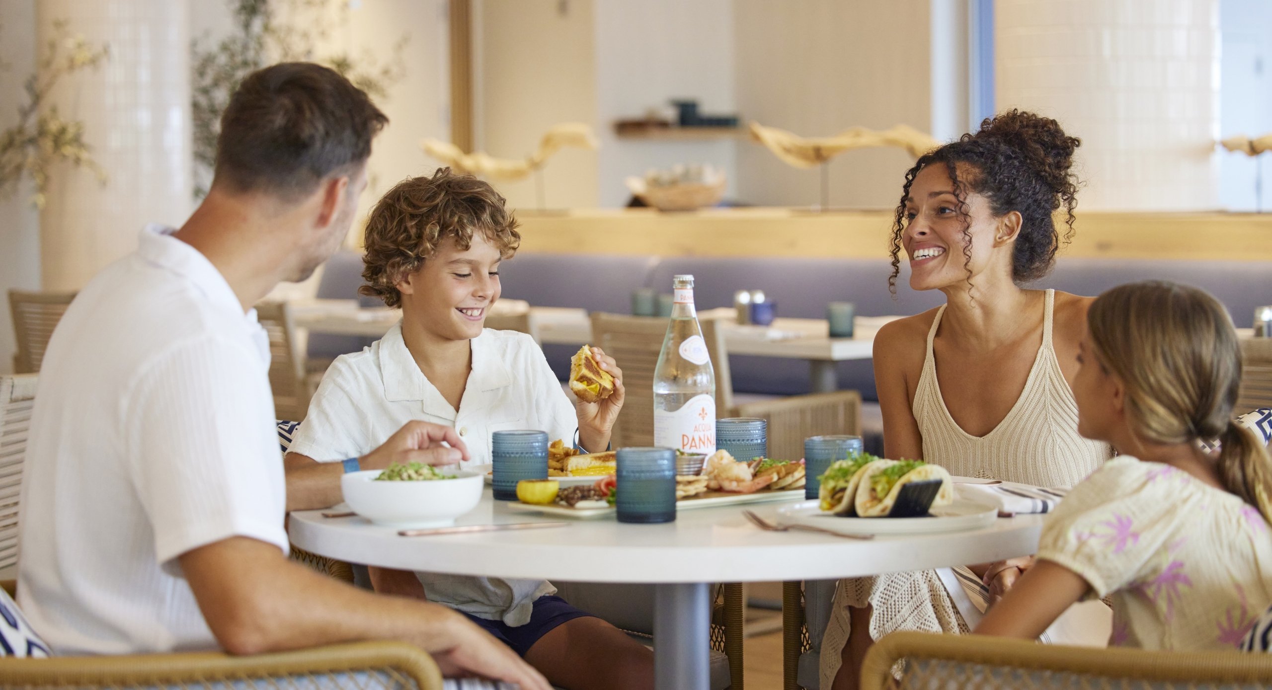 parents and two kids seated at table eating